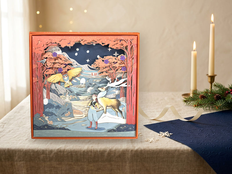 Assembled FOLDORI Sunrise Dreams paper diorama with its three story extensions on a festive table with candles, fir branches and fairy lights