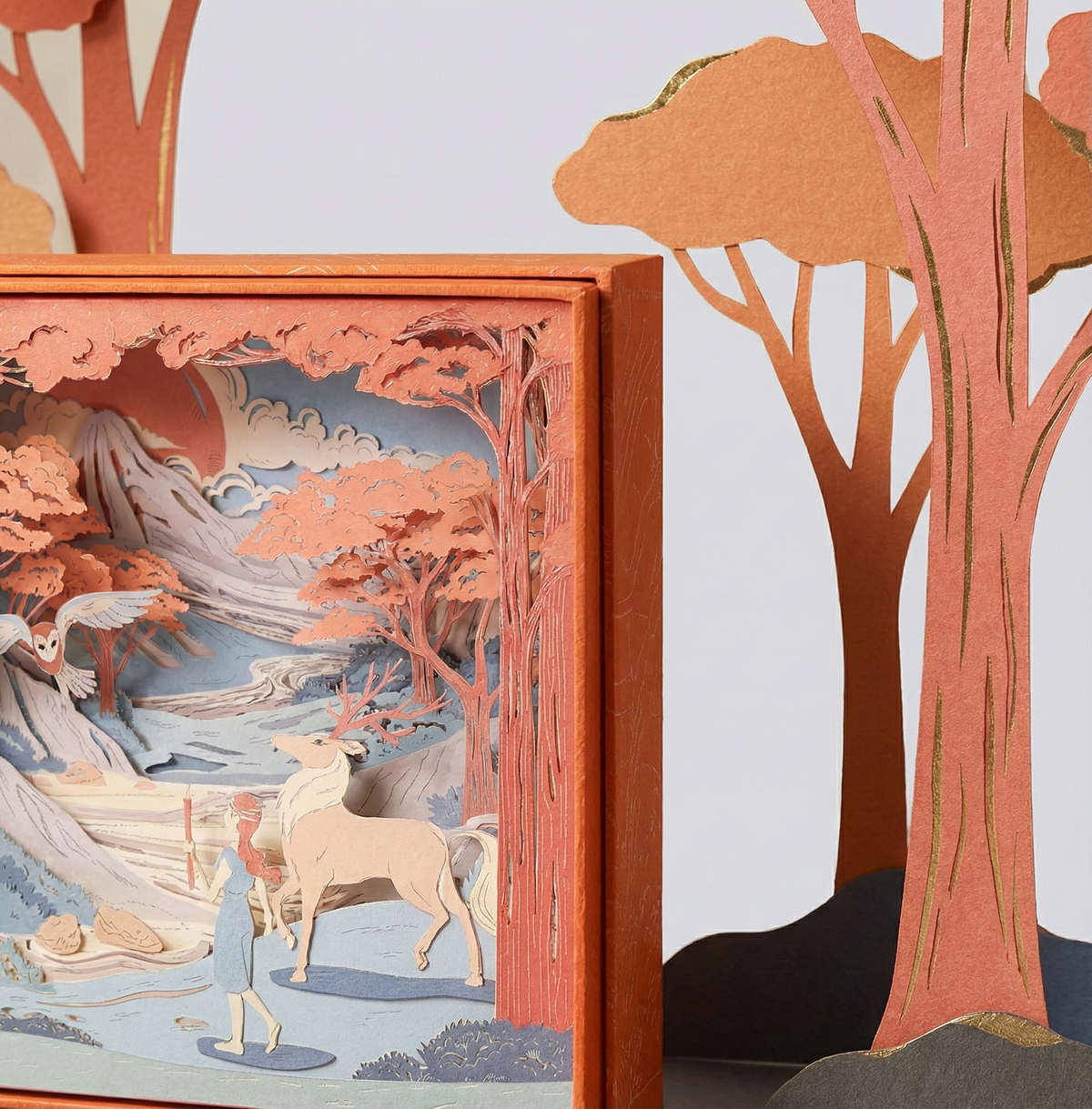 Side view of a layered paper diorama in a terracotta frame showing the depth between laser-cut landscape layers