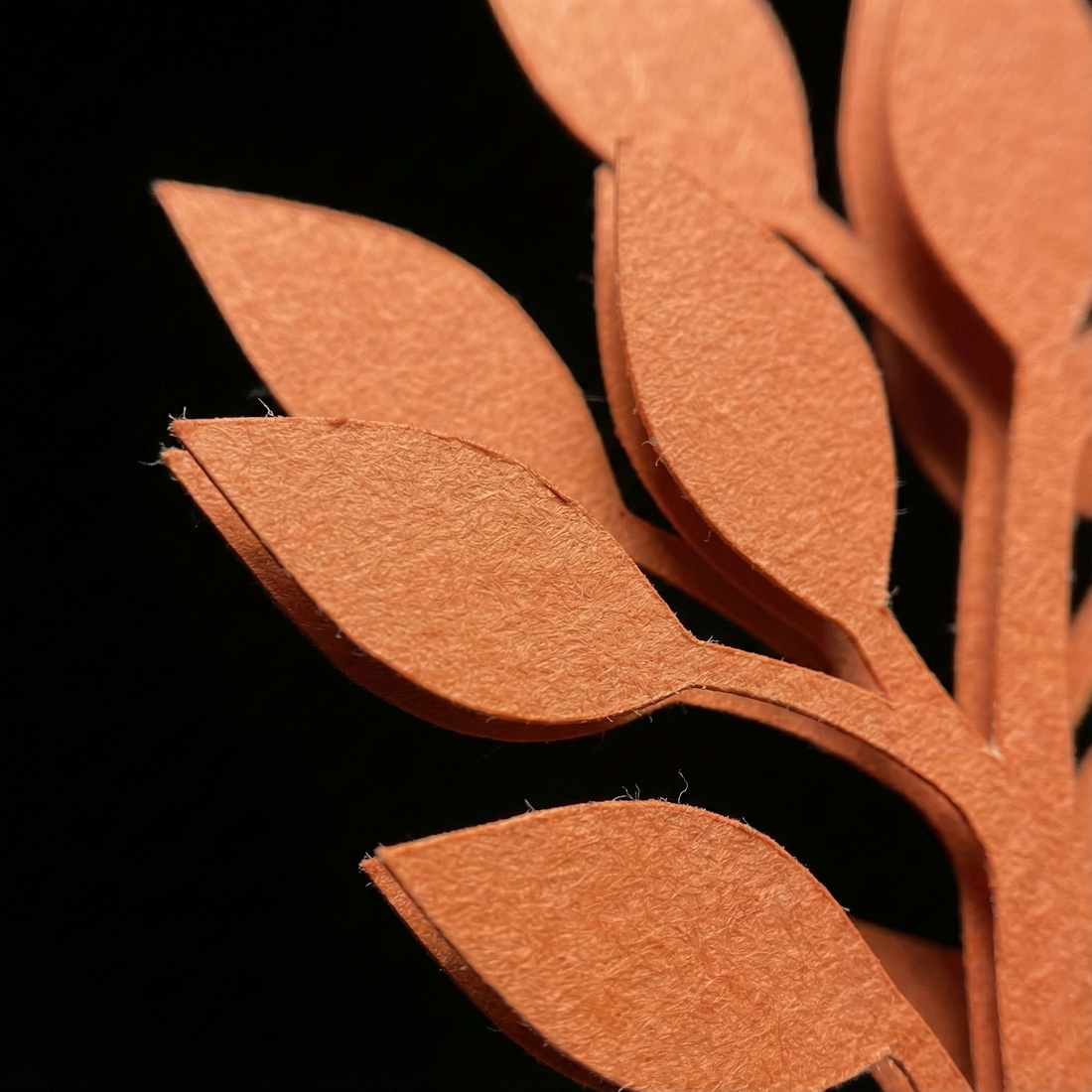 Close-up of laser-cut orange paper tree foliage with clean, crisp edges
