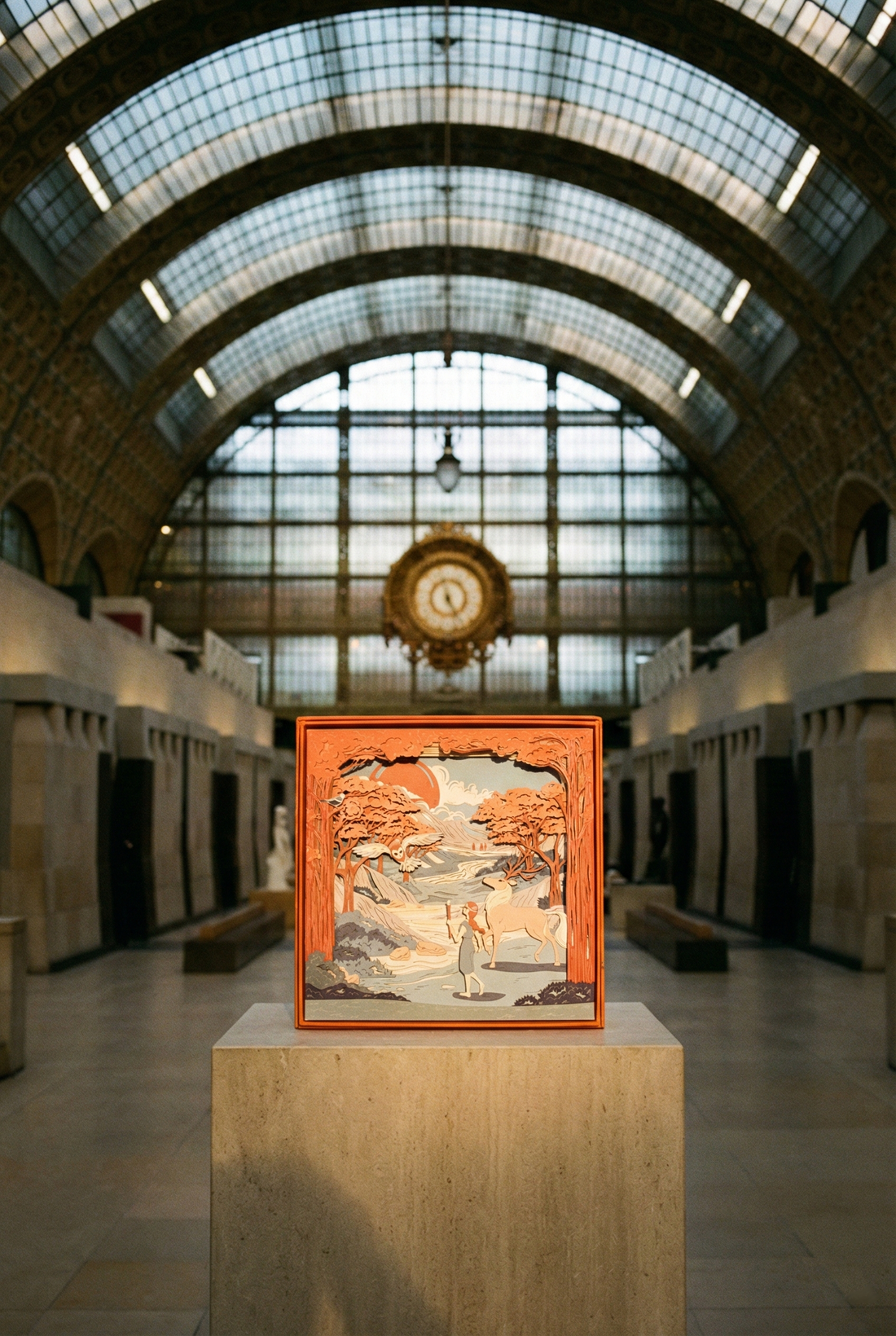 Sunrise Dreams paper diorama on a stone plinth in the hall of a grand museum with a glass roof