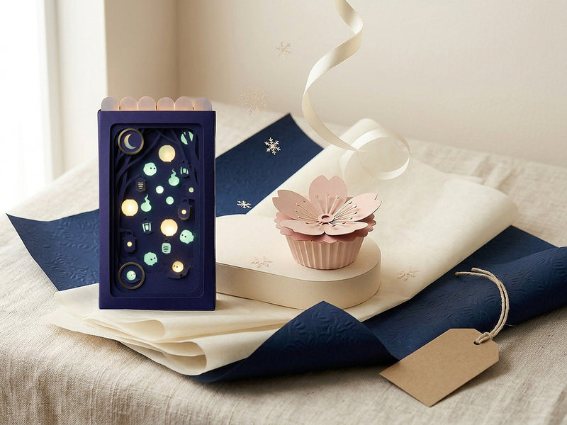 Fluorescent Spirits Pocket Story next to a Sakura Forever Paper Flower on a linen table