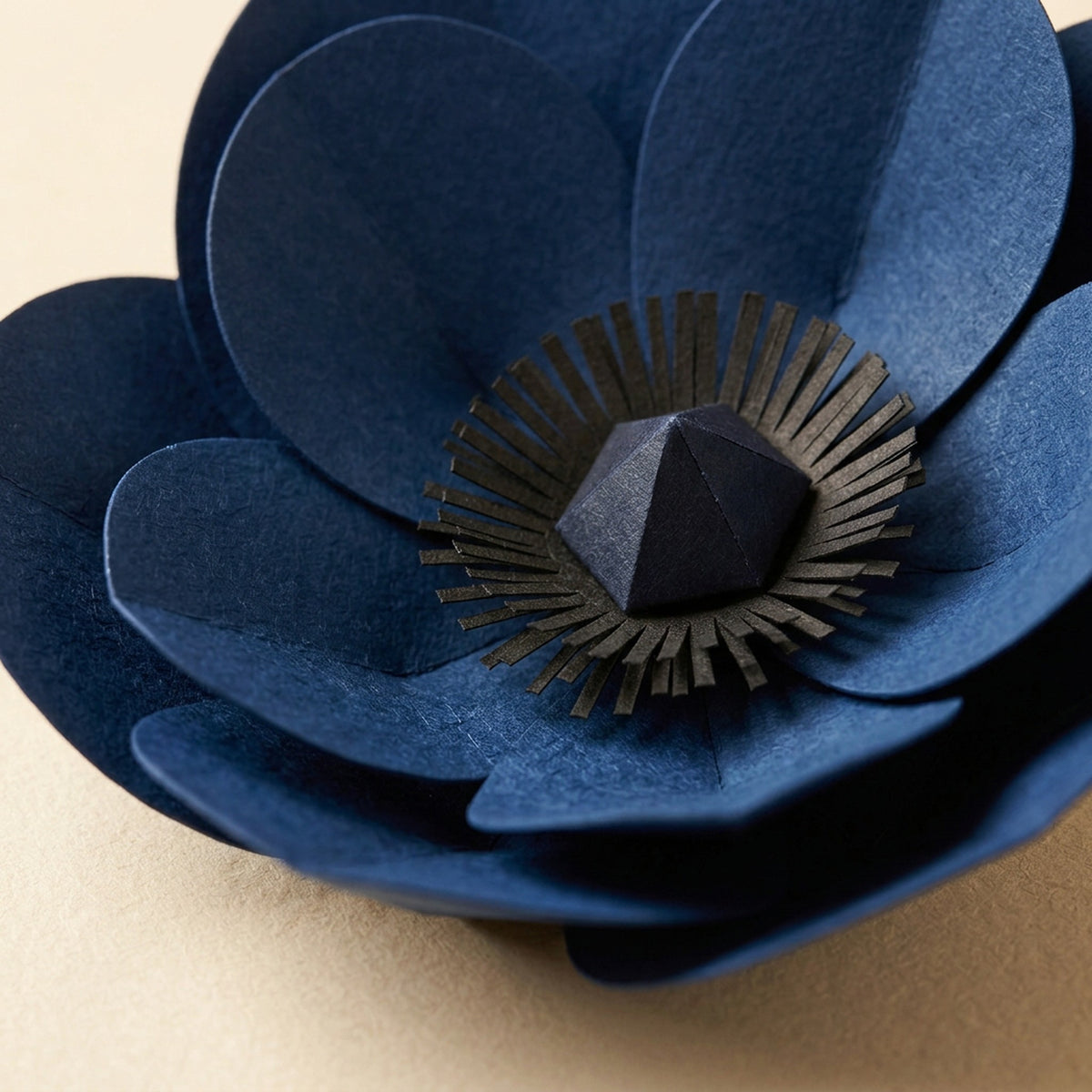 [CONCEPT PLACEHOLDER] Anemone paper flower in indigo on its pleated paper cup, close-up of the folded paper petals (AI concept image, not the final product)