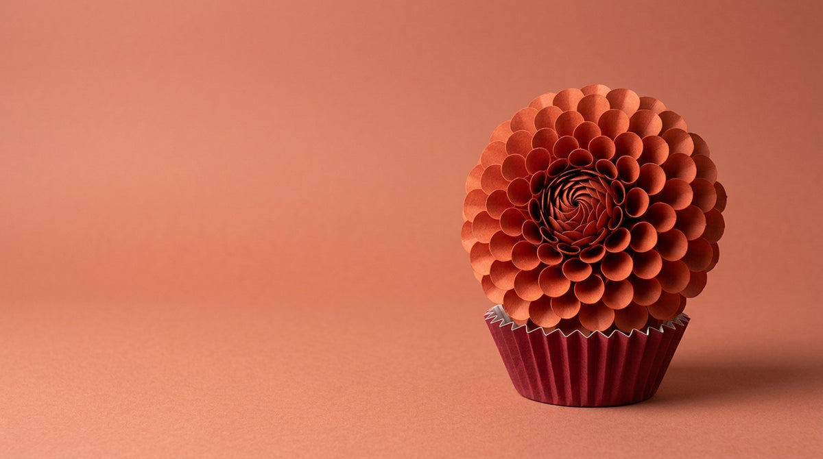 [CONCEPT PLACEHOLDER] Dahlia paper flower in sumac red on its pleated paper cup, colour moment on a tonal paper background (AI concept image, not the final product)