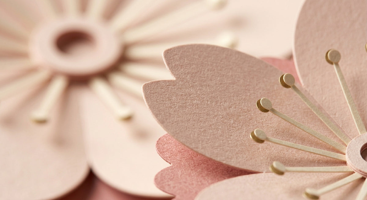 [CONCEPT PLACEHOLDER] Sakura paper flower in blush on its pleated paper cup, close-up of the folded paper petals (AI concept image, not the final product)