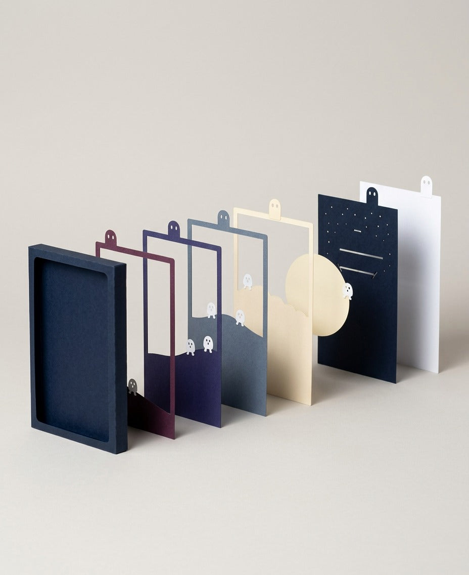 Fluorescent Spirits Pocket Story exploded view: navy sleeve, paper layers and moon disc