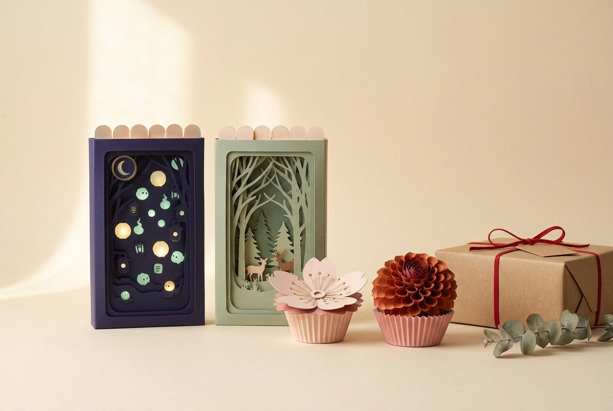 FOLDORI gift edit: two Pocket Stories sleeves, a sakura and a dahlia paper flower and a kraft gift box on cream paper